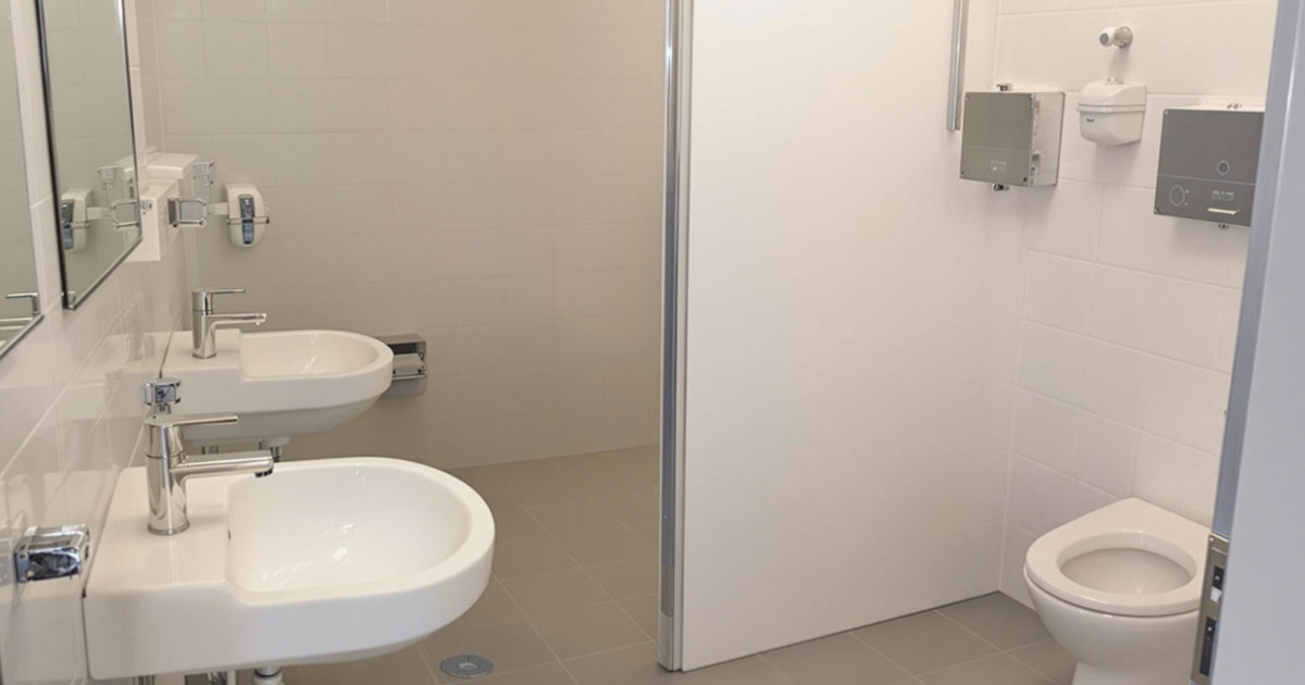 Projekt 371 zeigt einen modernen und hellen Toilettenraum mit weißen Sanitäreinrichtungen und Fliesen.